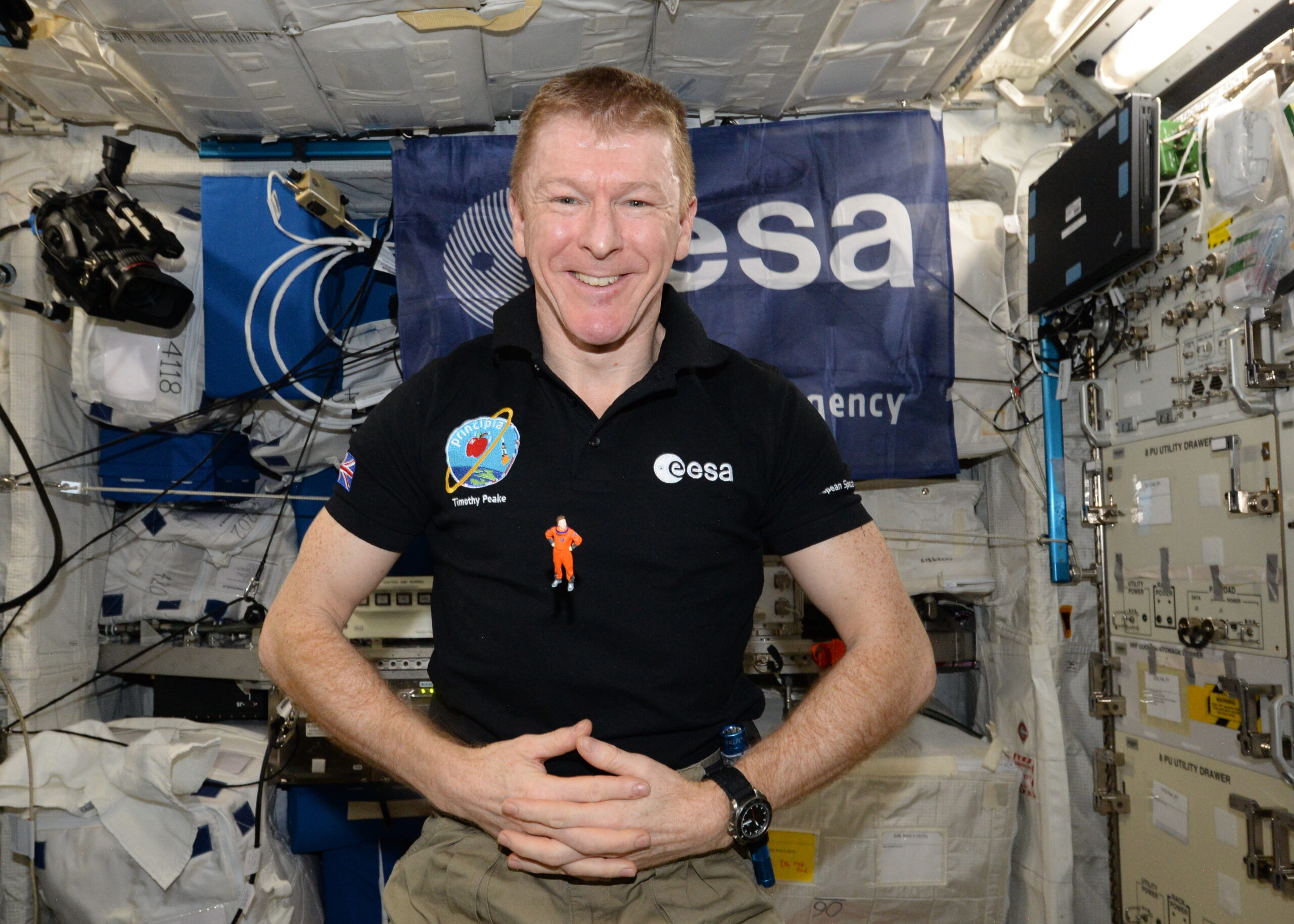 British Astronaut Tim Peake floating in space inside the International Space Station with a 6cm high plastic model called Mini Jon